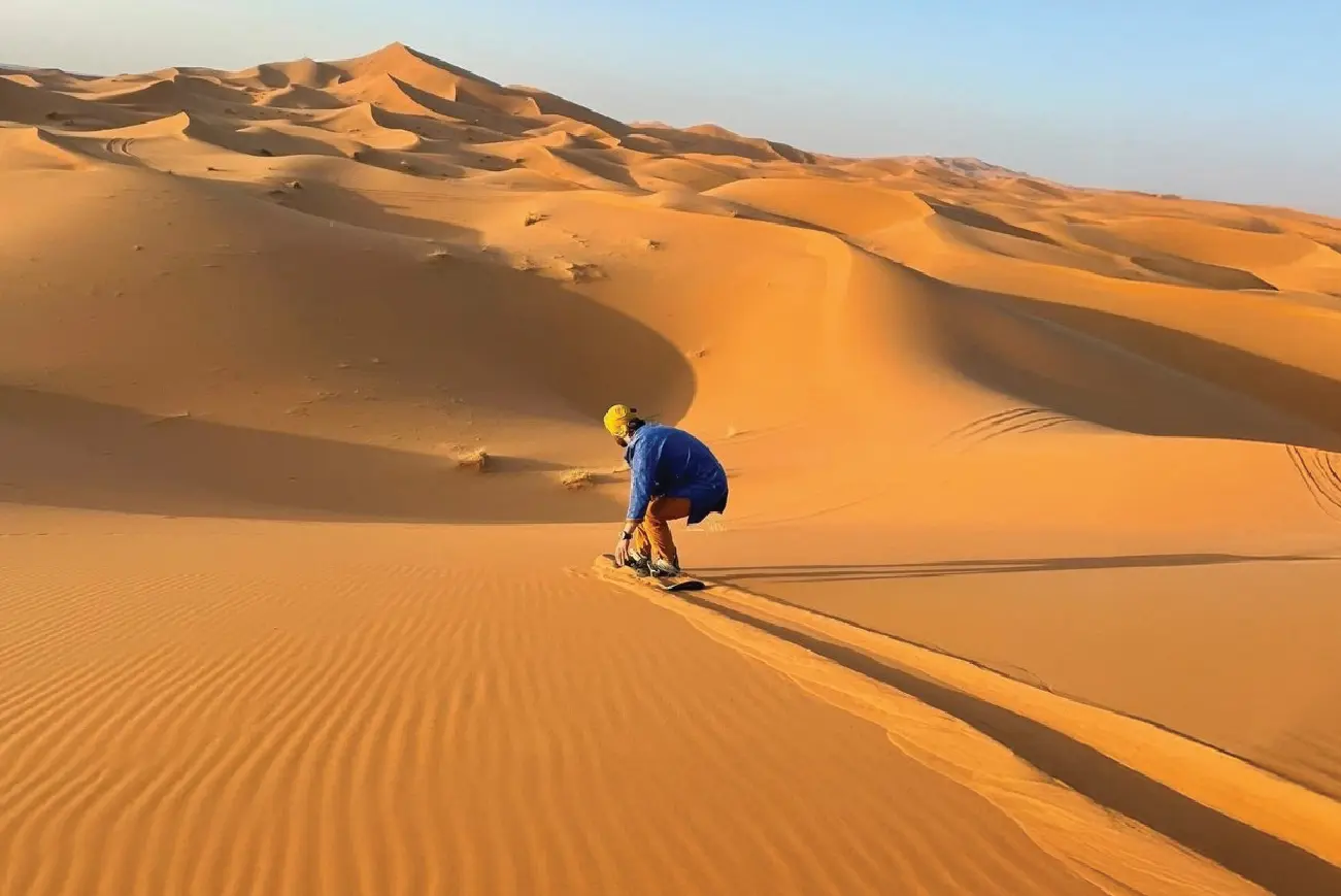 Rider on a quad bike crossing desert dunes
